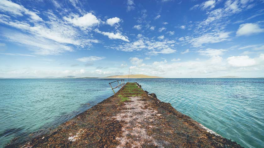 A pier leading out to sea on the Isle of Barra, Scotland.
