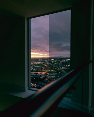 Looking out through a window at the sun setting over a city